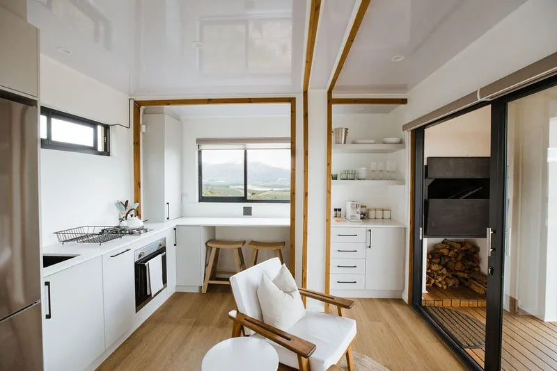 36m² 1-Bedroom Container House — Insulated Standard Configuration — supplier gallery view 8; Open-plan container house interior with a white kitchen, oven, timber ceiling battens and a built-in sleeping alcove