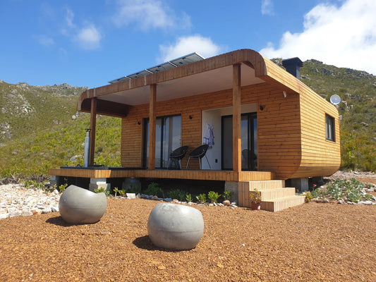 36m² 1-Bedroom Container House — Insulated Standard Configuration — supplier gallery view 1; One-bedroom container house clad in timber, with a covered veranda and raised gravel setting below a mountain slope