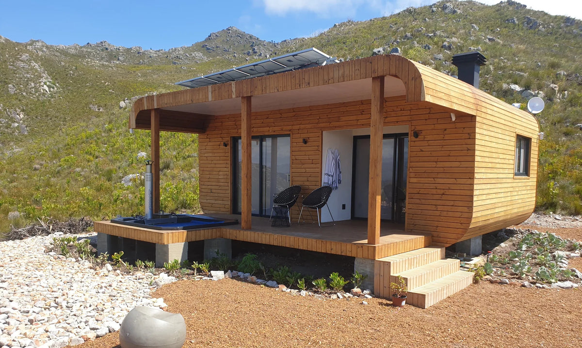 36m² 1-Bedroom Container House — Insulated Standard Configuration — supplier gallery view 2; Timber-clad one-bedroom container house with veranda, plunge pool and roof-mounted solar panels against the mountains