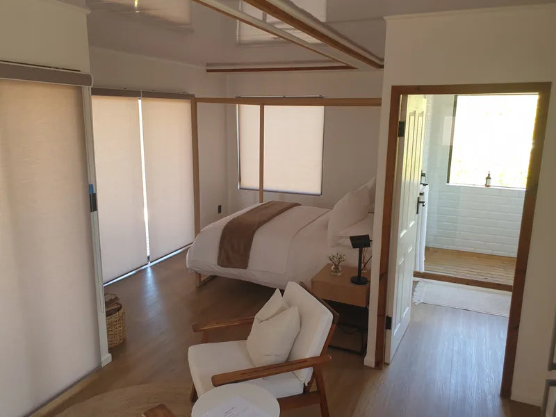 36m² 1-Bedroom Container House — Insulated Standard Configuration — supplier gallery view 5; Container house bedroom with a made bed, armchair and blinds, with the bathroom visible beyond
