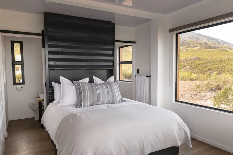 104m² 3-Bedroom Container House — Insulated Standard Configuration — supplier gallery view 5; Bedroom with a double bed, black slatted headboard wall and a window looking onto open veld