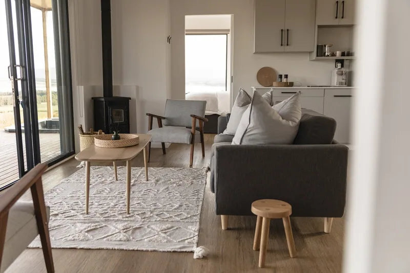 104m² 3-Bedroom Container House — Insulated Standard Configuration — supplier gallery view 3; Open-plan living area with a sofa, timber coffee table, rug and a wood-burning stove beside glazed doors
